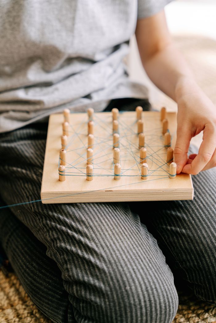 A child interacts with a geoboard, promoting mindful learning through play.